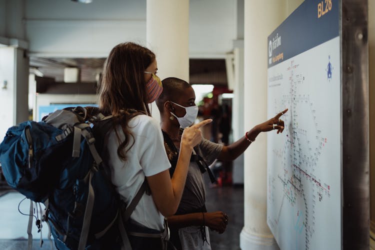 Photograph Of Tourists Pointing At A Map