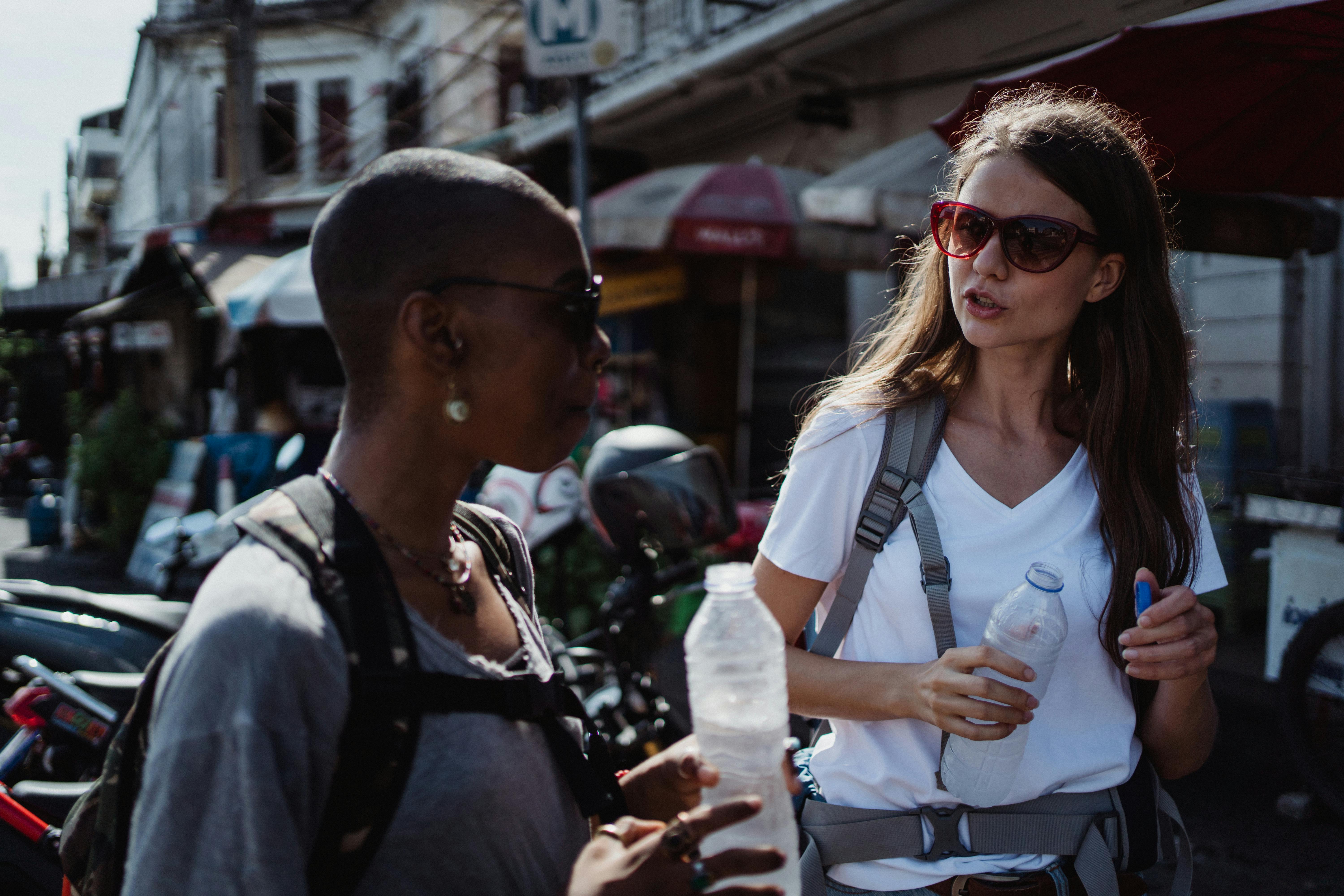 Two Friends Talking to Each Other while Holding Plastic Bottles