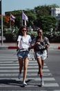 两名女子笑着跑过人行横道，周围是充满活力的城市环境