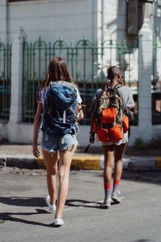 Two young adults walking with backpacks in a vibrant urban setting.