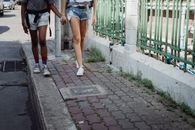 阳光明媚的日子里，两名妇女手牵着手走在人行道上