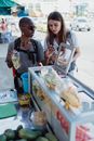 两名女子在旅行中探索当地美食，浏览街头小吃摊