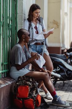 Two women travelers checking a map outdoors, exploring a city street.