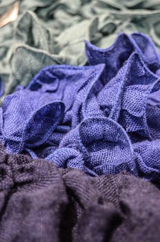 Colorful crumpled knitted fabrics in blue and green create a rich textile texture.