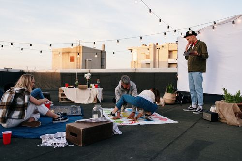 Free Friends enjoying a fun game night on a rooftop with lights and snacks. Stock Photo