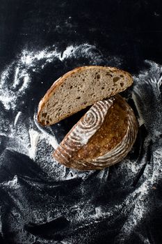 Top view of sliced sourdough bread on a black table covered with flour.