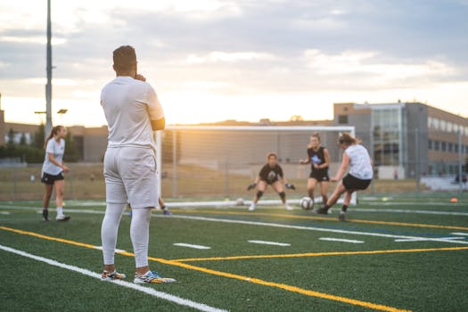 Female athletes training in soccer at sunset, focusing on teamwork and skill development on an outdoor field.