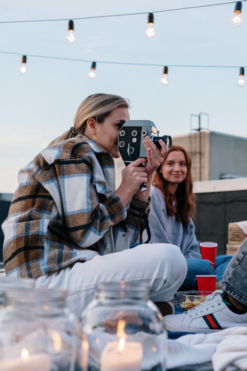 Woman in Brown and White Plaid Dress Shirt and Blue Denim Jeans Sitting on Red Chair