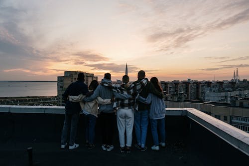 Group of People Standing on Top of Building during Sunset
