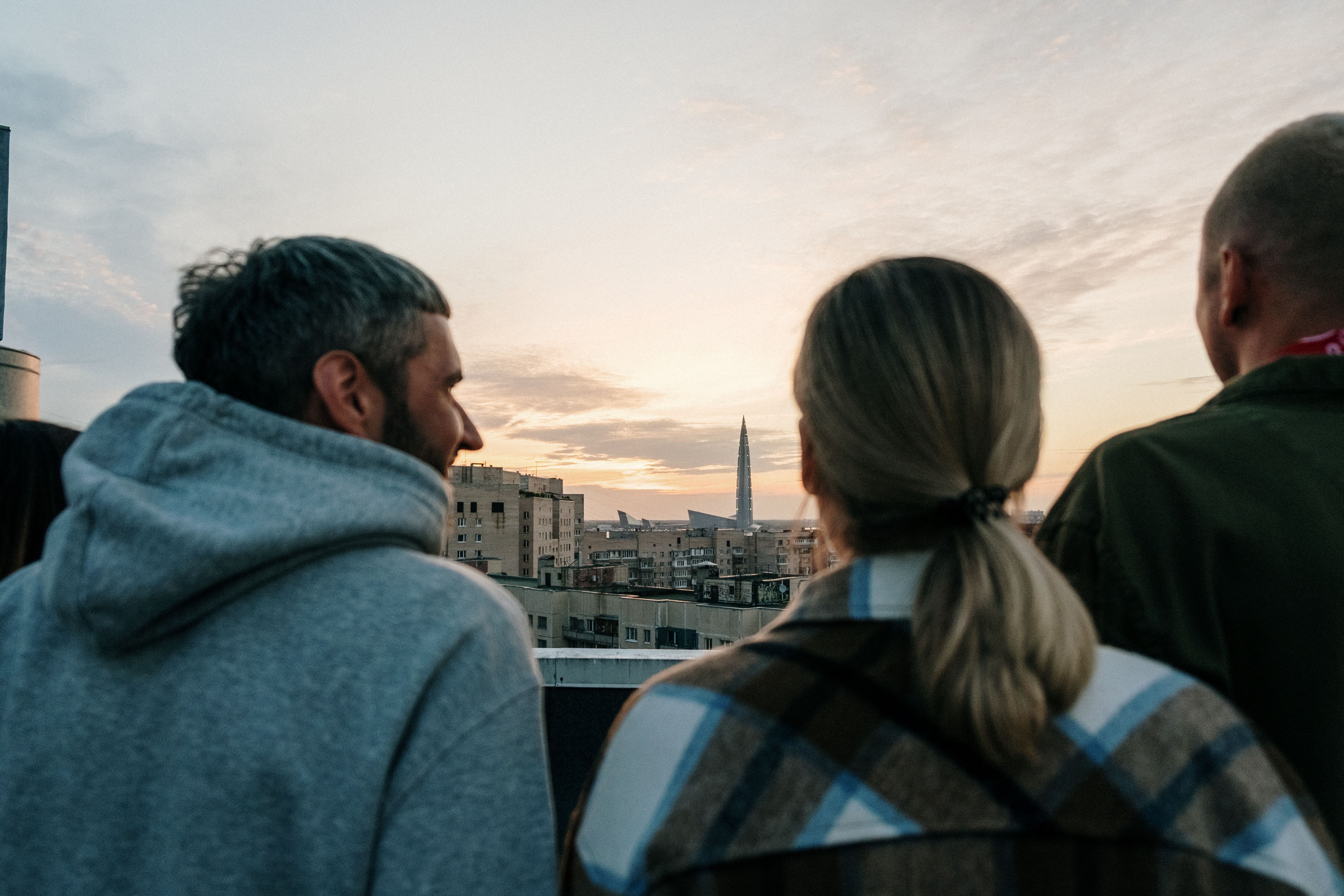 Friends sitting together on a rooftop watching the sun set over a city