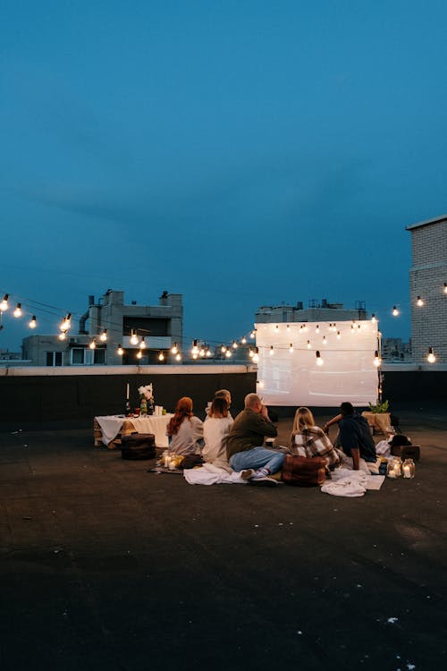 Free People Sitting on Ground Near Body of Water during Night Time Stock Photo