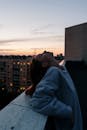 日落时分，一名女子在屋顶上俯瞰城市景观，享受着宁静的时刻