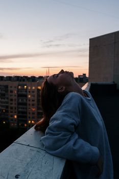 日落时分，一名女子在屋顶上俯瞰城市景观，享受着宁静的时刻