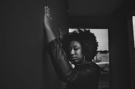 Black and white portrait of a confident woman against a city wall in an urban setting.