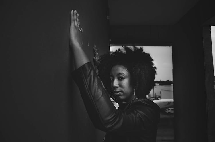 Young Black Woman Standing On Street With Hands On Wall