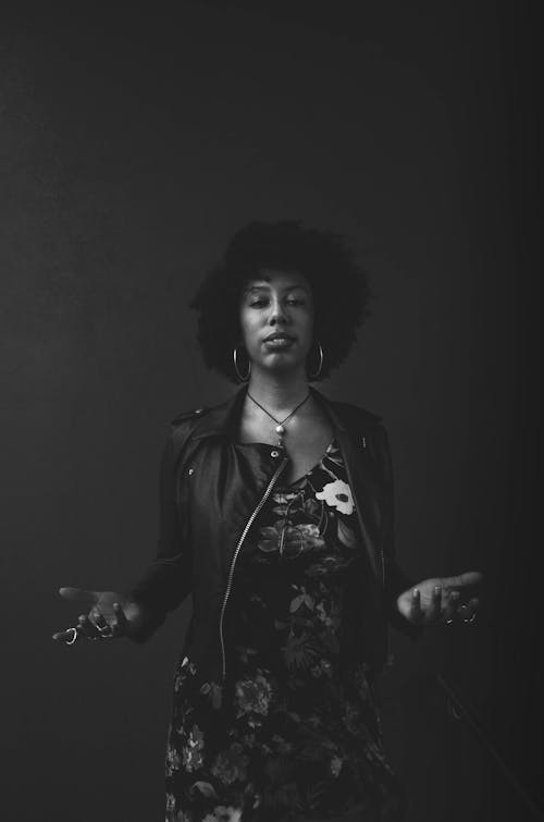 Free Serious black woman shrugging hands against dark background Stock Photo