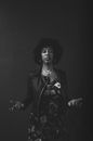 Serious black woman shrugging hands against dark background