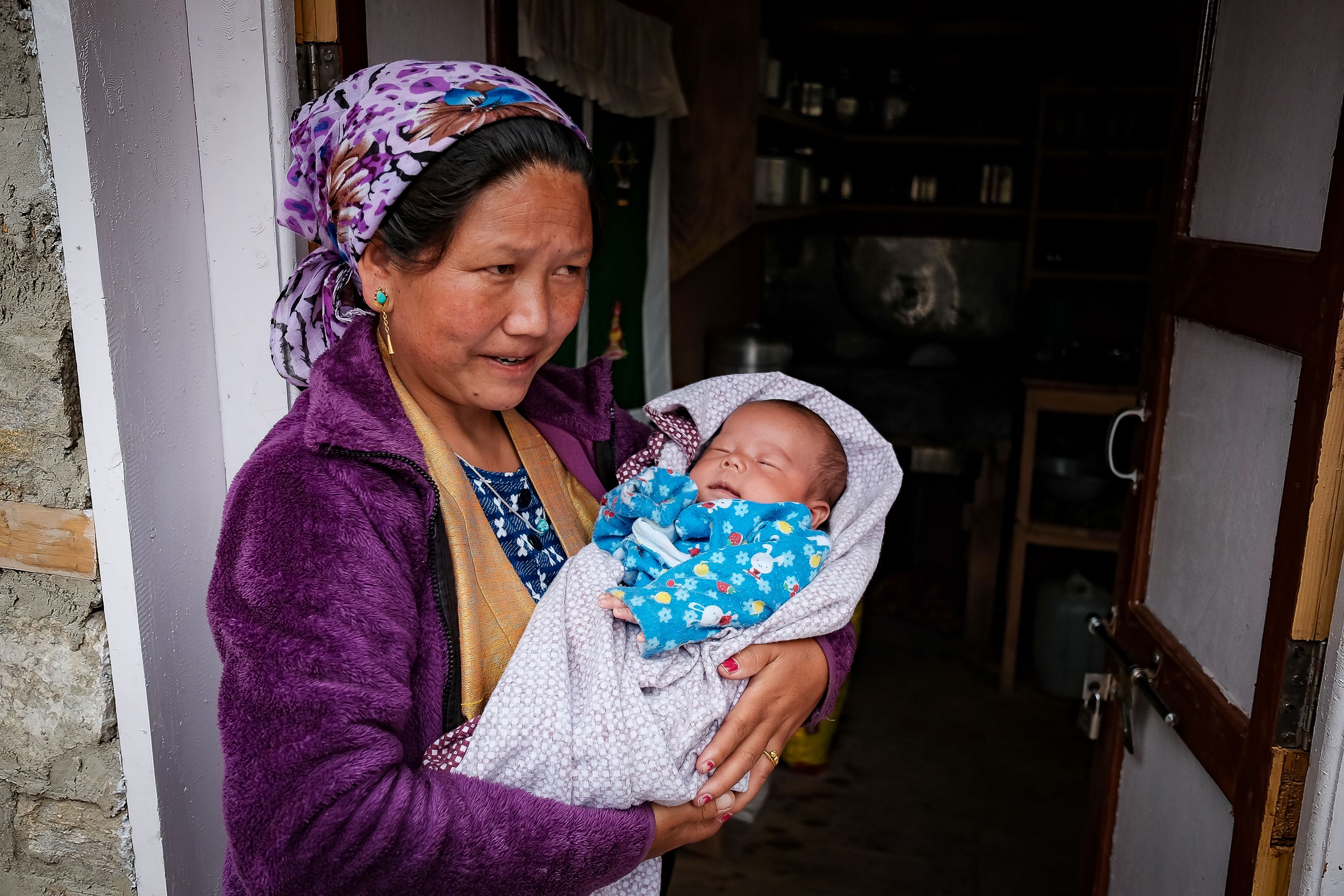 Nepali woman cradling a baby in Syapru Besi, capturing warmth and maternal love.