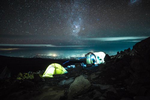 Free Illuminated tents on Kilimanjaro under a stunning starry sky, capturing the essence of nighttime adventure. Stock Photo