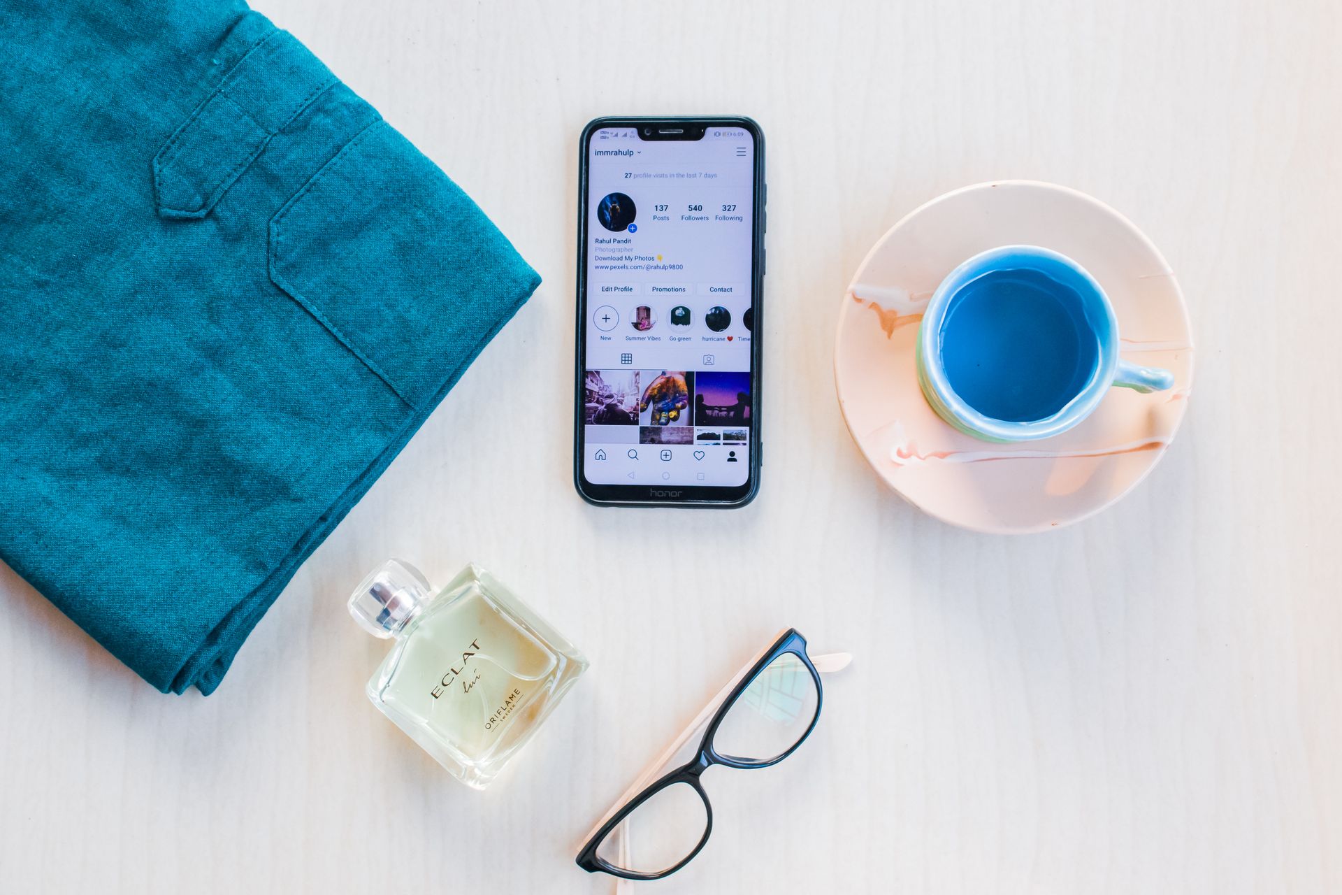 Smartphone screen near cup with blue beverage on white background