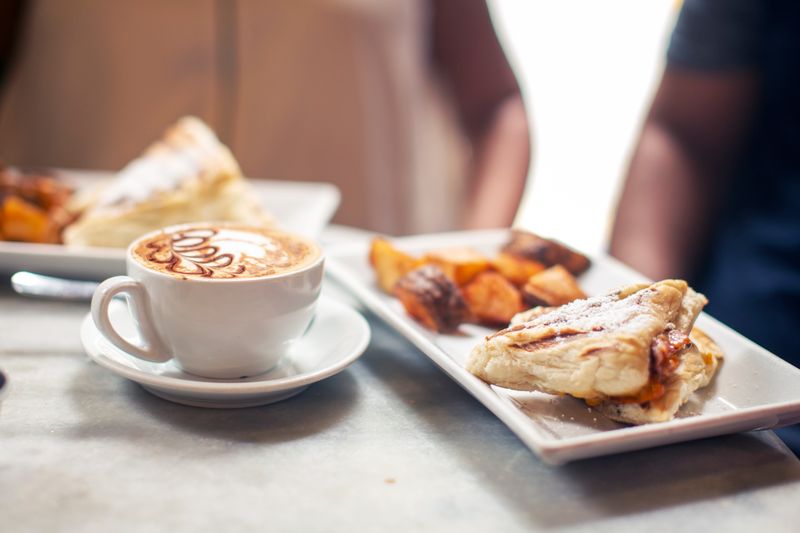 Cappuccino beside a warm breakfast pastry