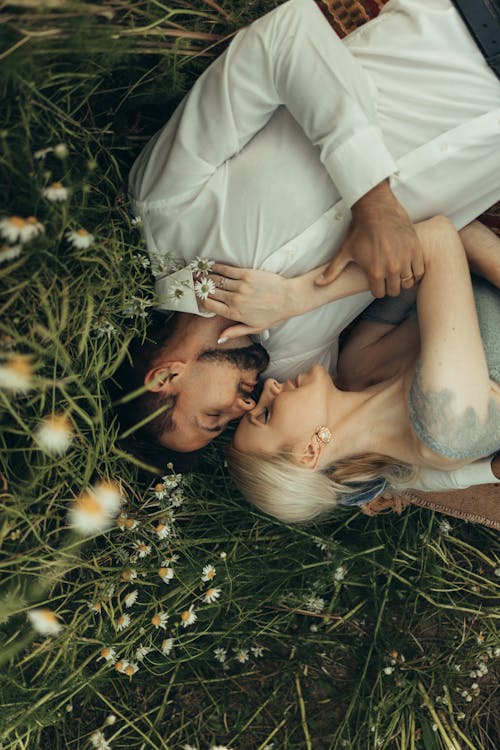 Free Romantic Couple Lying Down on Grass Next to Each Other Stock Photo