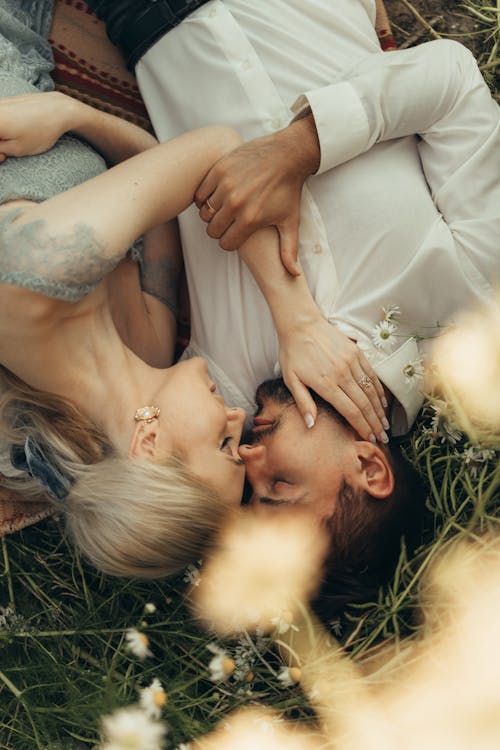 Free Romantic Couple Lying Down on Grass Next to Each Other Stock Photo