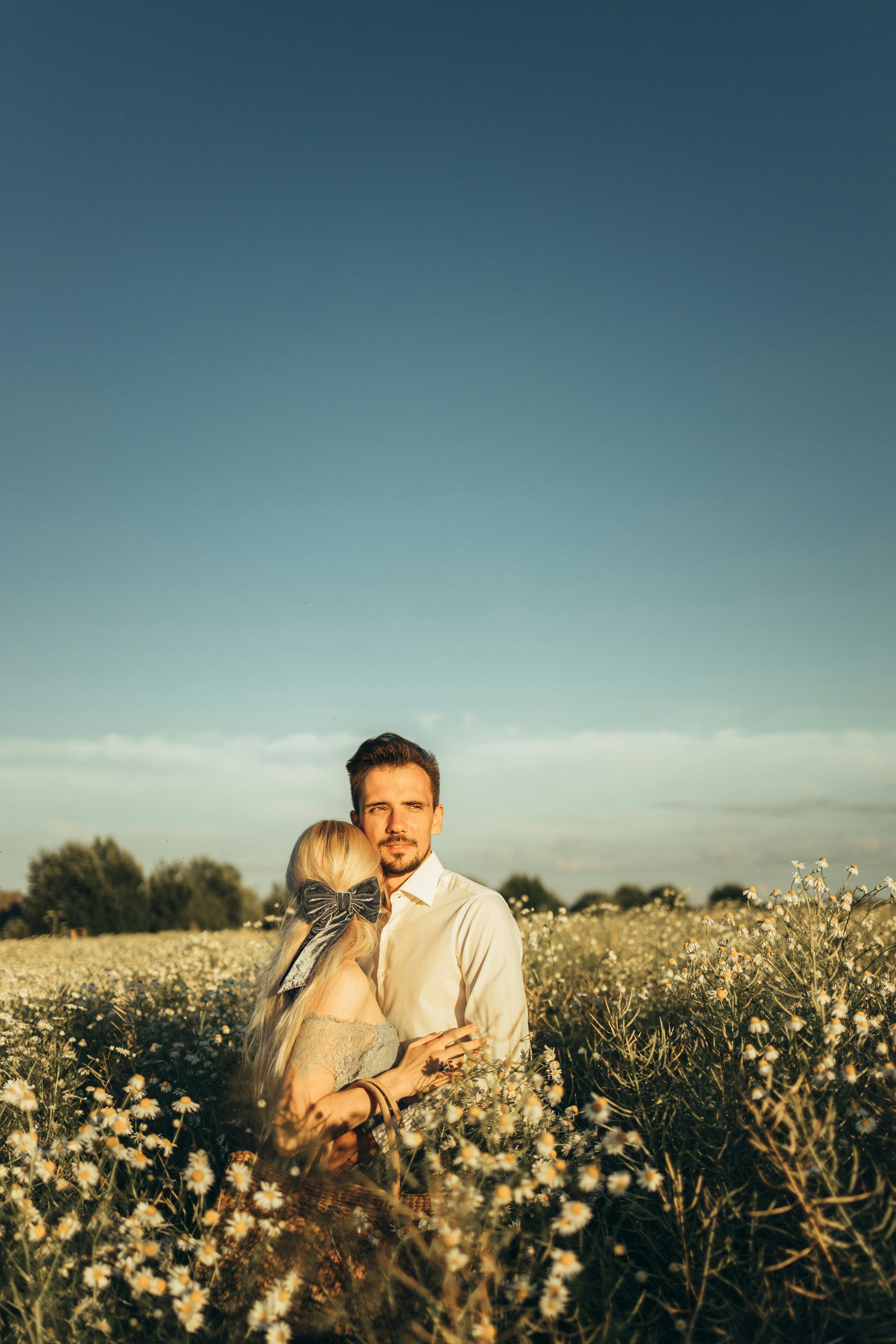 一对夫妇在晴朗的蓝天下，拥抱于郁郁葱葱的洋地黄田中