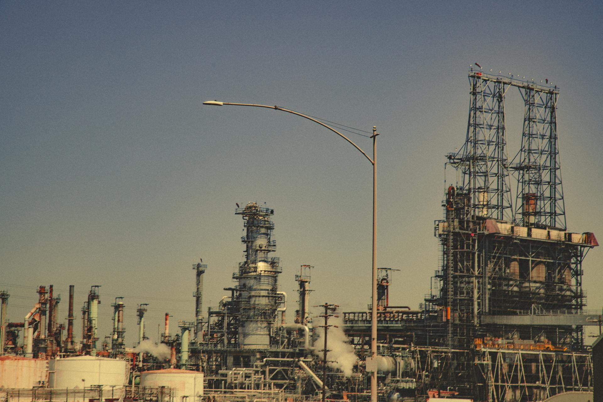 A large industrial refinery with pipes and towers under a clear blue sky during the day.