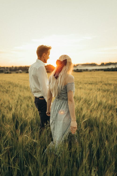 Couple Standing on Grass Field while Holding Hands