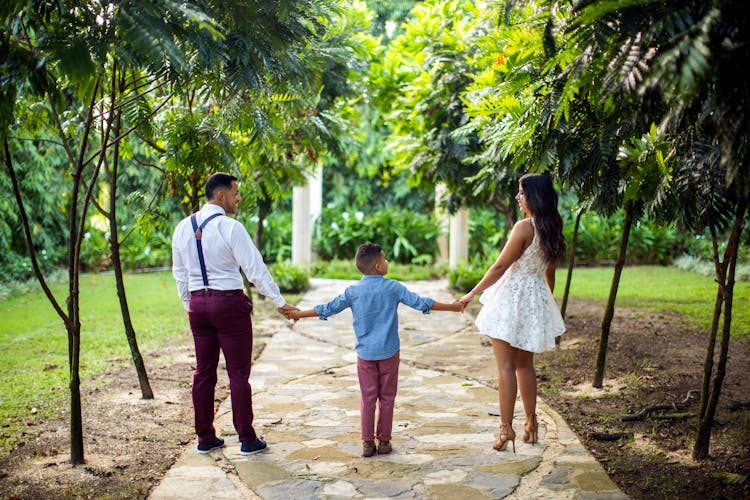 Stylish Ethnic Family Holding Hands And Walking In Park