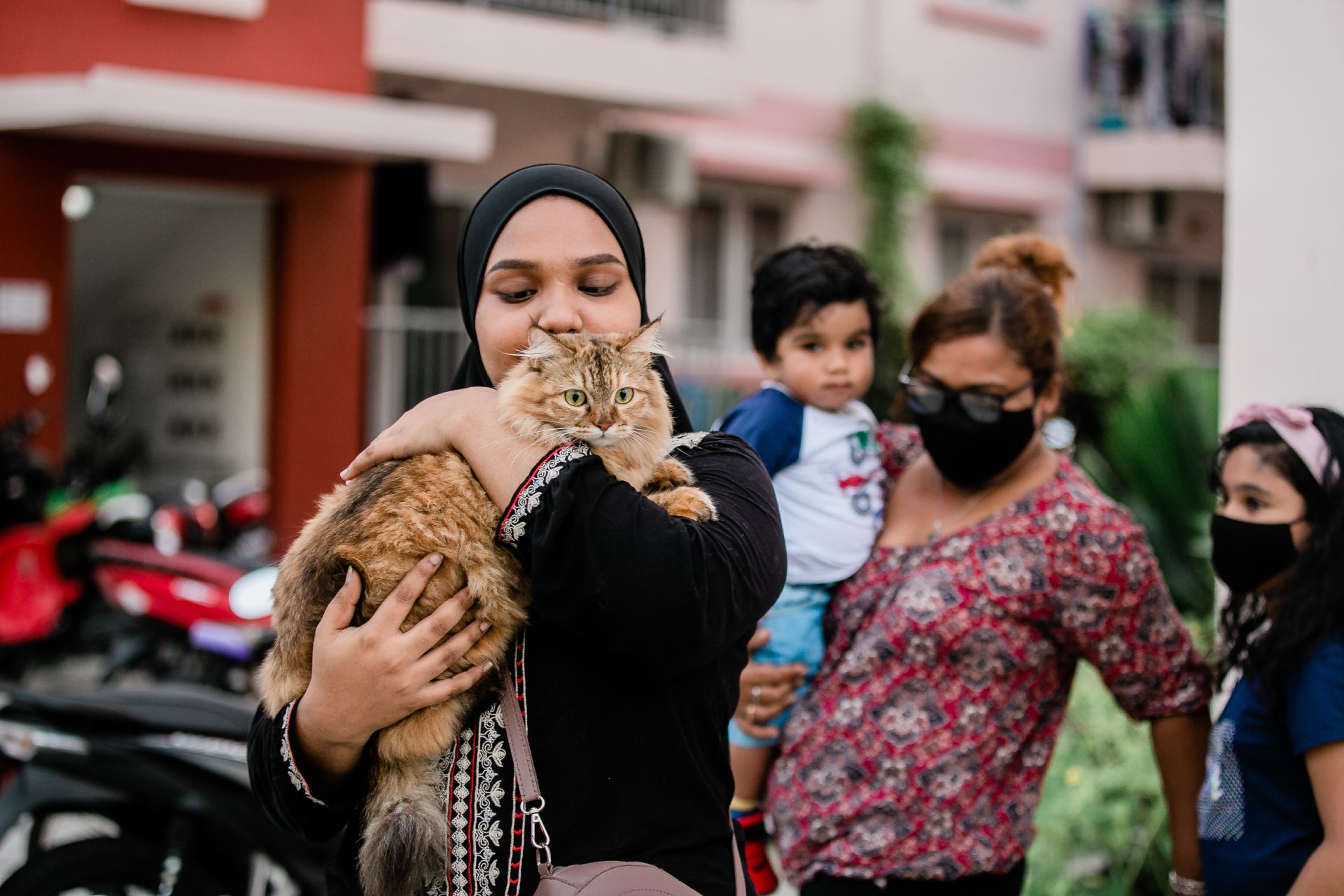 Woman in Black Long Sleeve Shirt Carrying a Brown Tabby Cat
