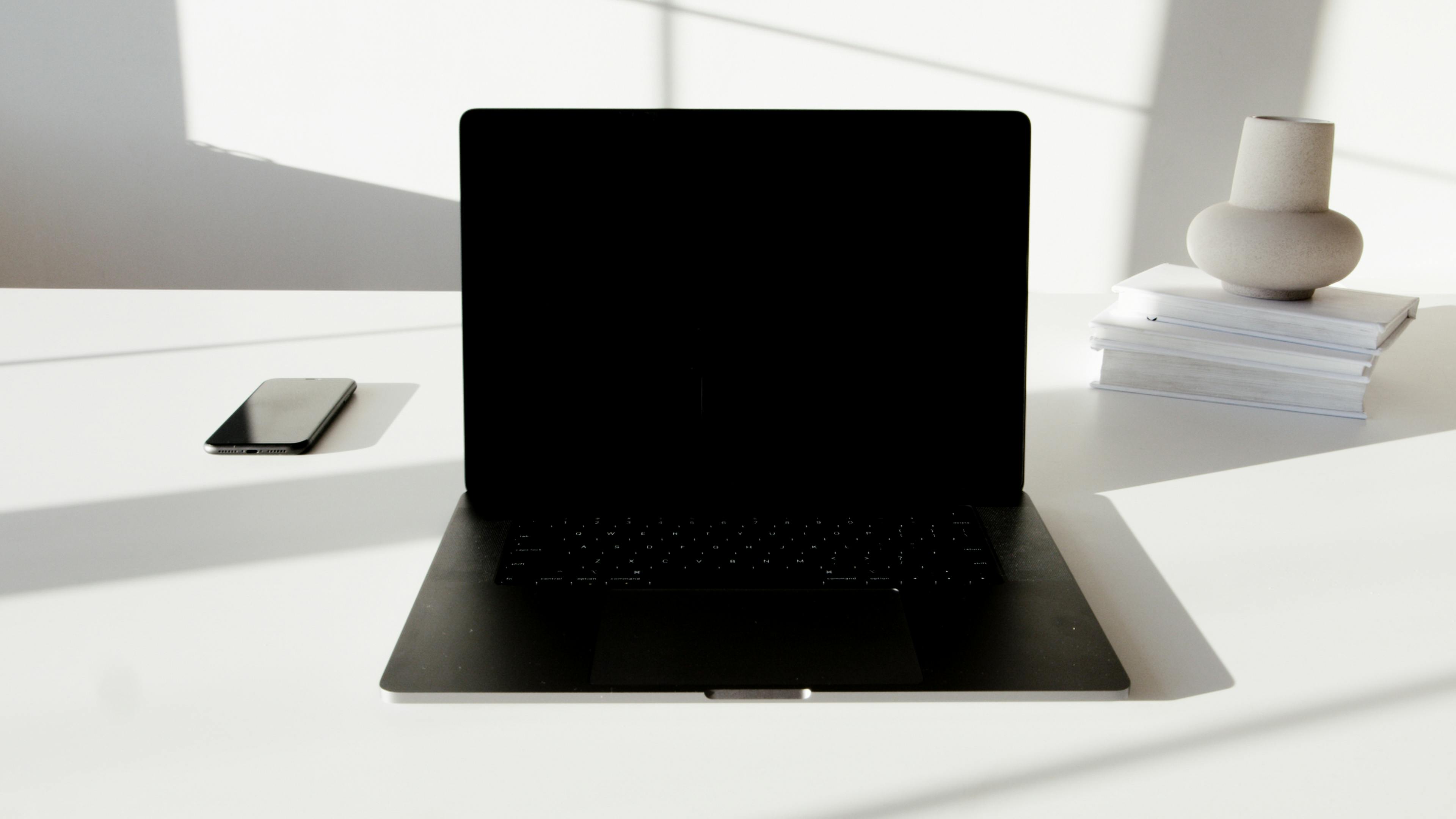 Kleines, helles Home Office im Wohnzimmer mit weißem Schreibtisch, ergonomischem Stuhl und Wandregal