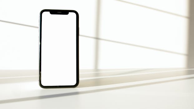 A sleek smartphone displayed on a white surface with dramatic light and shadow contrast.