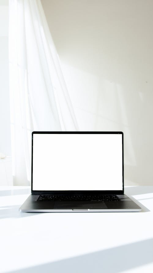 Free Black Laptop with White Screen on White Table Stock Photo