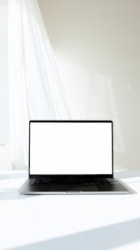 明亮的室内表面上，现代笔记本电脑的极简主义实体模型有着白色屏幕