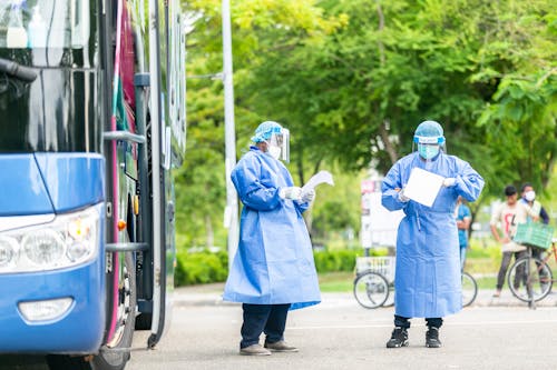 People in Personal Protective Equipment Standing on the Street