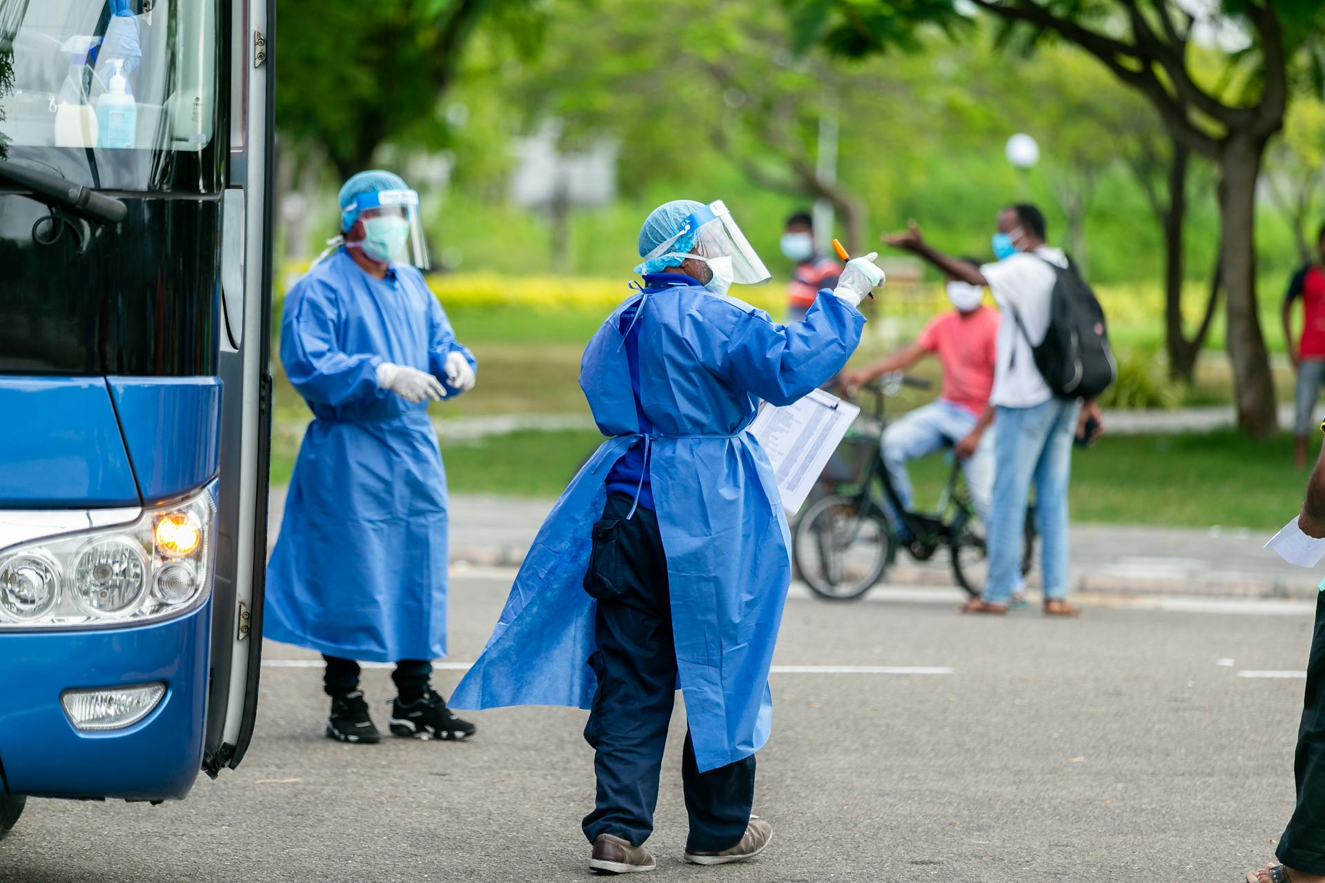 Healthcare workers in PPE managing COVID-19 checkpoint outdoors during pandemic.