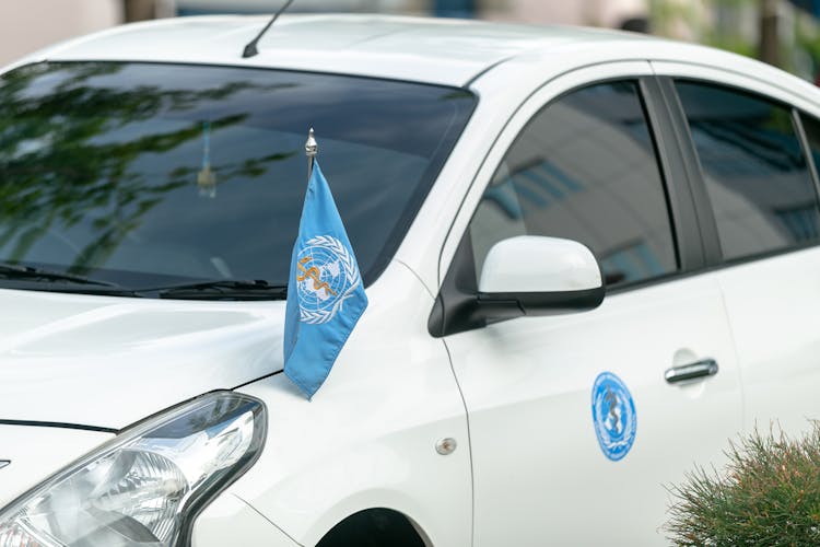 Modern White Car With World Health Organization Flag And Sticker