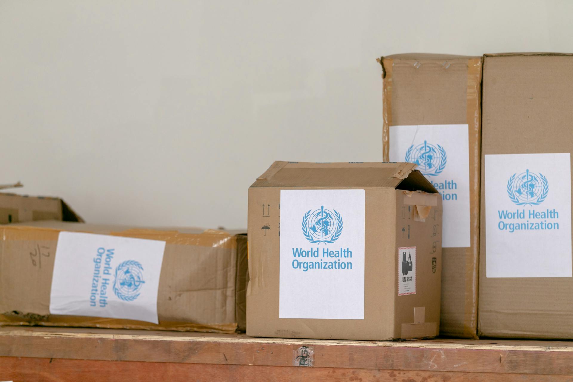 Blue emblem sticker of World Health Organization on carton boxes heaped on table
