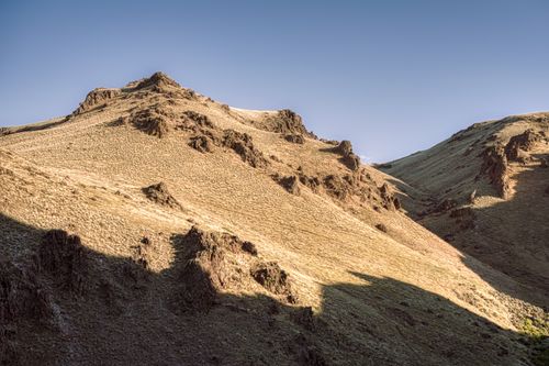 Free Picturesque view of bristly mounts with brown sand under blue cloudless sky in daylight Stock Photo