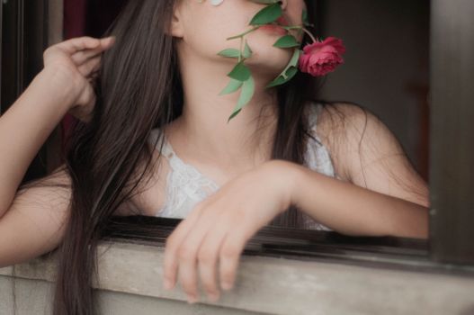 一幅精致的女性肖像，长发飘逸，嘴里叼着玫瑰，散发着性感和美丽