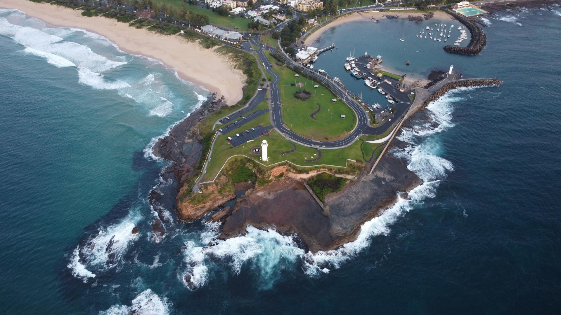 A stunning aerial view of the Wollongong lighthouse, coastline, and harbor in NSW, Australia.