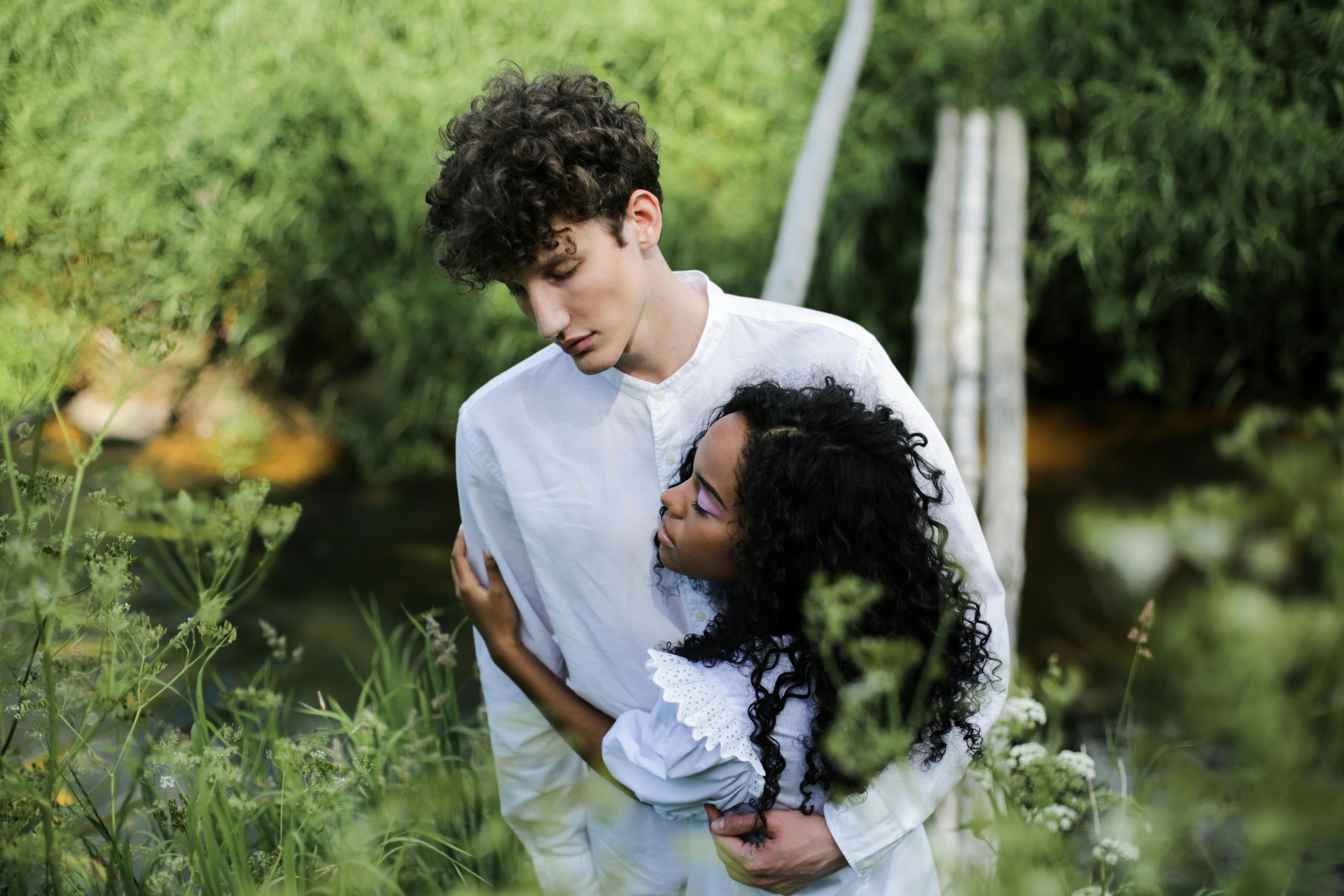 man in white crew neck t shirt and white pants holding black dog