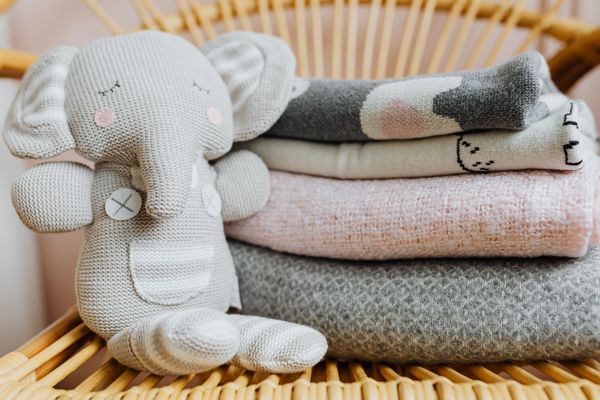 Knitted elephant toy on folded pastel baby blankets — photo by Kaboompics on Pexels