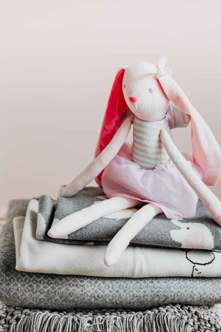 A Stuffed Toy Sitting On Folded Blankets