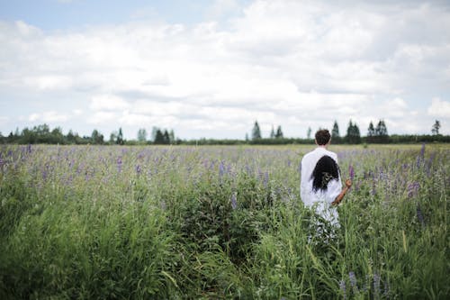Man in White Shirt Standing on Green Grass Field
