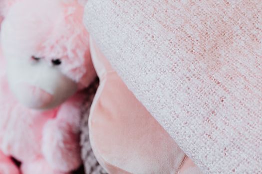 A textured pink blanket paired with a cute plush toy bear for a cozy feel.