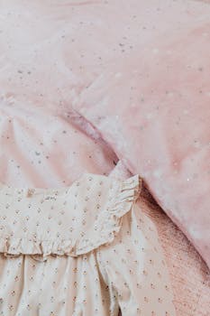精致的婴儿连衣裙与柔软的粉色星纹床上用品相搭配
