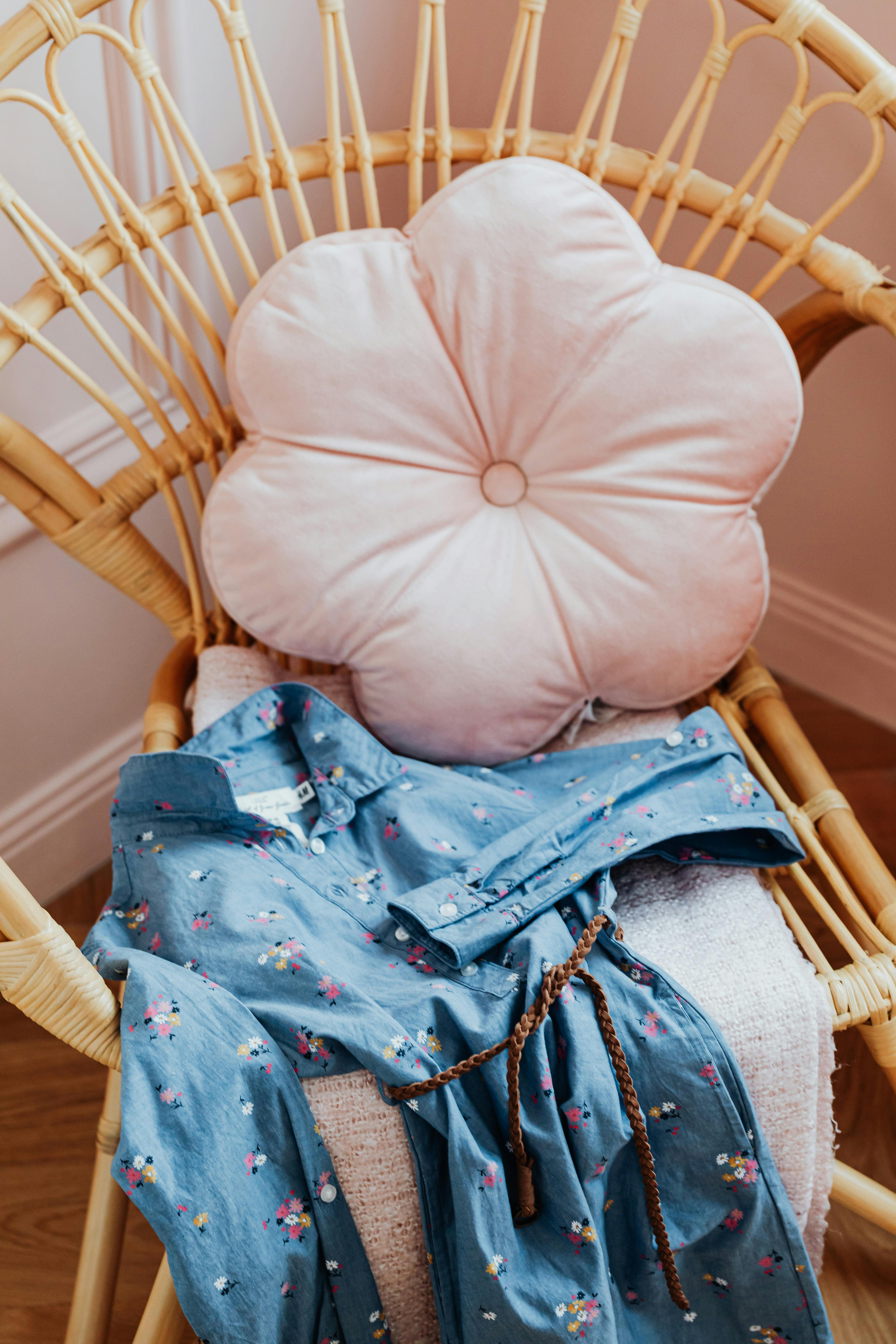 遮阳椅上披着一件花卉牛仔连衣裙，搭配着柔软的粉色花朵形枕头